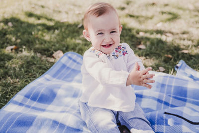 Portrait of smiling girl sitting on towel at park