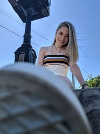 Portrait of smiling woman sitting against sky