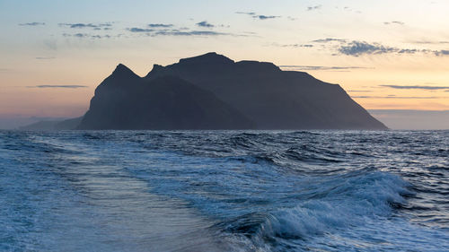 Scenic view of sea and silhouette mountain against sky during sunset