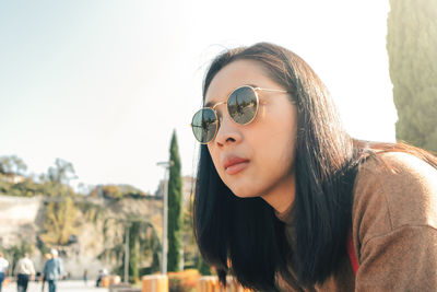 Portrait of young woman wearing sunglasses against sky