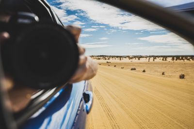 Rear view of person photographing car on landscape