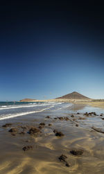 Scenic view of beach against clear blue sky