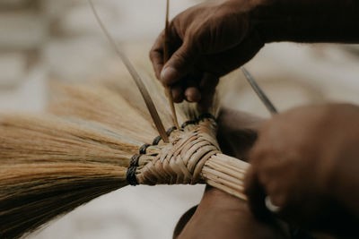 Close-up of person working on handcrafted walis tambo or brooms