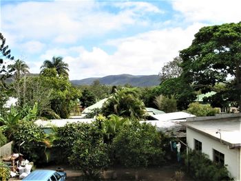 Trees by swimming pool by building against sky