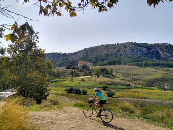 Woman riding bicycle on street against sky