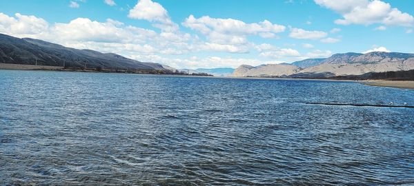 Scenic view of lake by mountains against sky