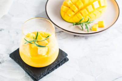 Mango smoothie in glasses and sliced mango on a plate on the table. homemade dessert