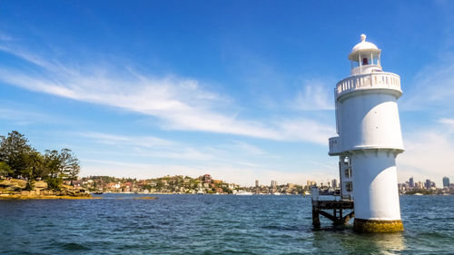 Lighthouse by sea against sky