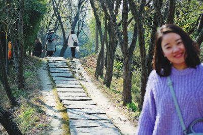 Portrait of woman standing on footpath tree in forest