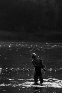 Shirtless boy standing in river at night