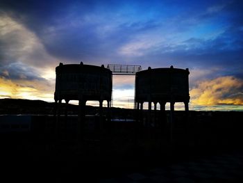 Silhouette water tower against sky during sunset