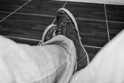 Low section of man wearing shoes on tiled floor
