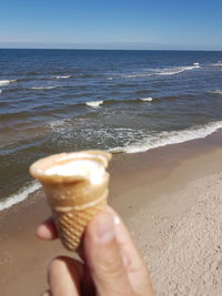 Close-up of hand holding ice cream on beach