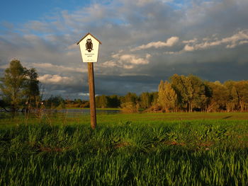 Information sign on field against sky
