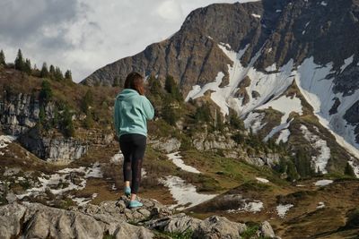 Rear view of woman standing on rocks against mountain