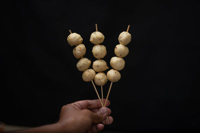 Close-up of hand holding ice cream against black background