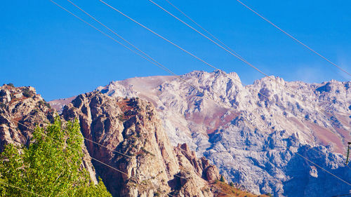 Low angle view of snowcapped mountains against clear blue sky