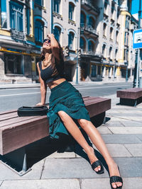 Woman sitting on bench in city