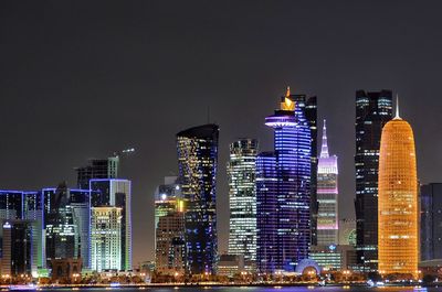 Illuminated buildings in city against sky at night