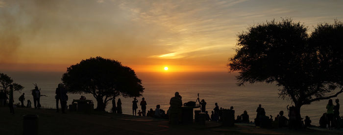 Silhouette trees by sea against sky during sunset