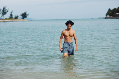 Shirtless man swimming in sea