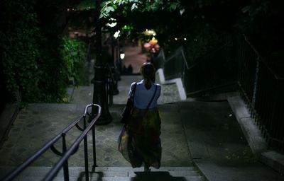 Rear view of woman walking on steps at night