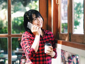 Young man holding coffee cup by window