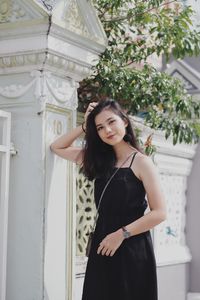 Portrait of young woman standing by building in city