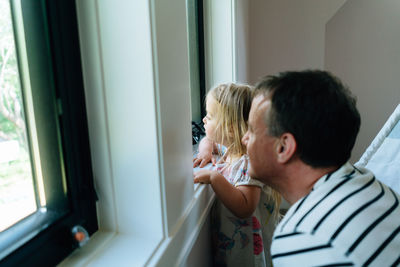 Side view of a father and daughter looking at a window