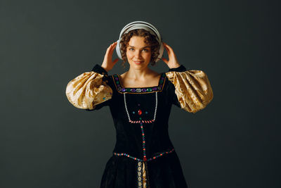 Portrait of young woman standing against black background