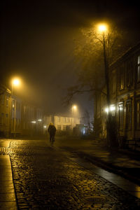 Man walking on illuminated street at night