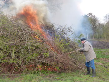 Farmer with gardening fork working by bonfire