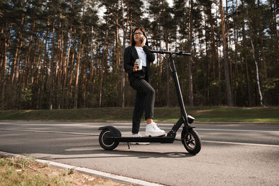 Low angle view of woman talking over smart phone while standing on road