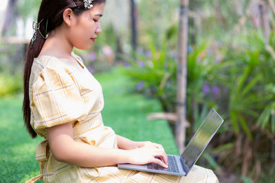 Side view of young woman using mobile phone