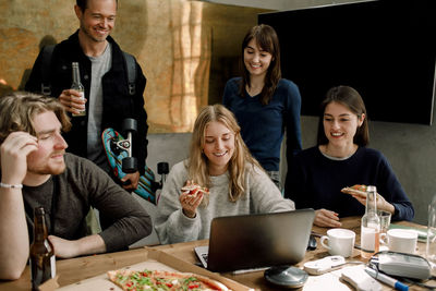 Smiling professionals eating pizza while working in office