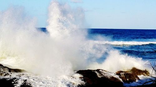 Waves splashing on sea against sky