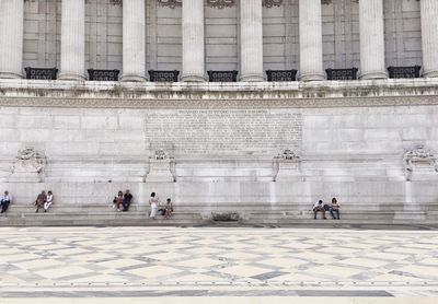 People sitting next to historical building