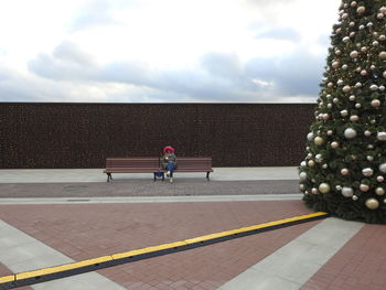 Woman sitting on bench against sky during christmas