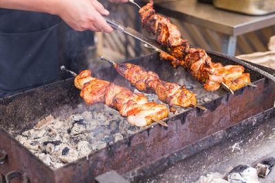 Person holding meat on barbecue grill