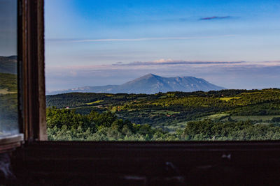 Scenic view of landscape against sky seen through window