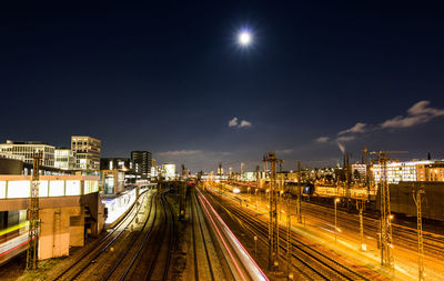 Illuminated railroad tracks against sky at night