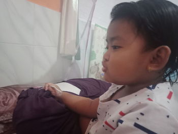 Portrait of boy looking away while relaxing on bed at home