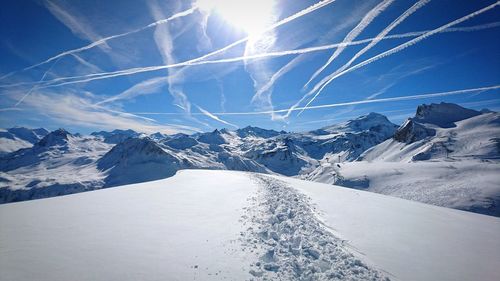 Vapor trails in sky over snow covered mountains