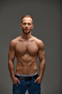 Portrait of shirtless man standing against black background