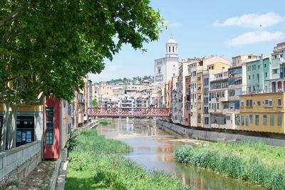 Buildings by river against sky in city