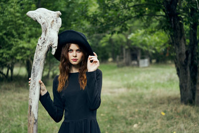 Portrait of young woman standing against trees