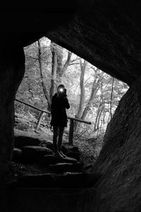 Rear view of woman standing on rock in forest