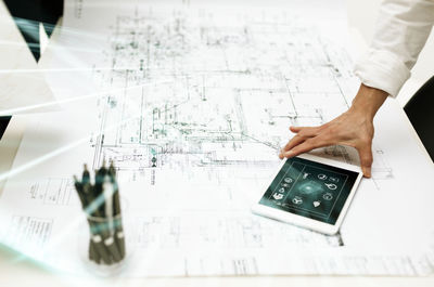 Architect using digital tablet on whiteprint