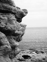 Rock formation by sea against sky