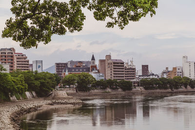 Buildings by river against sky